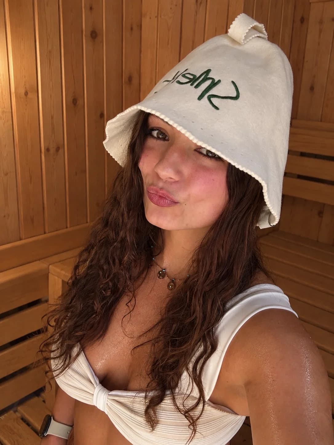 Woman wearing a Natural Cream Smelt sauna hat in a wooden sauna